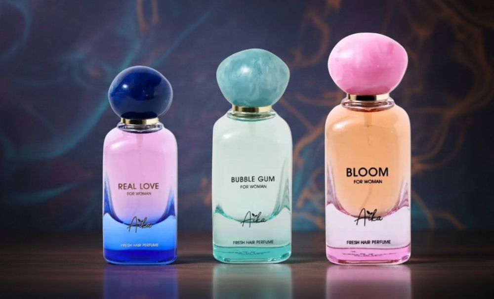 Three perfume bottles labeled 'Real Love', 'Bubble Gum', and 'Bloom' on a dark background.