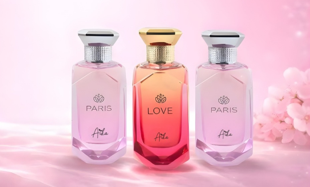 Three perfume bottles with 'Paris' and 'Love' labels on a pink background