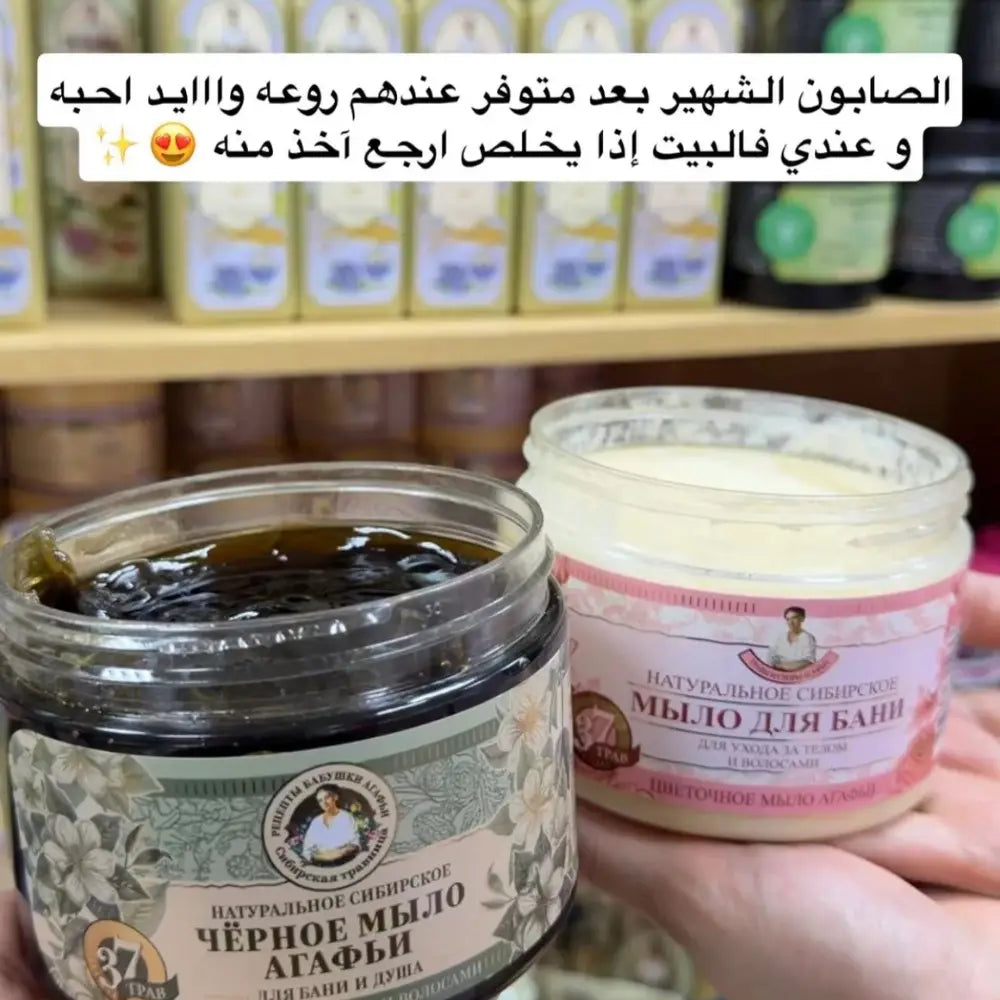 Two jars of soap held in front of a shelf with more soap bars.