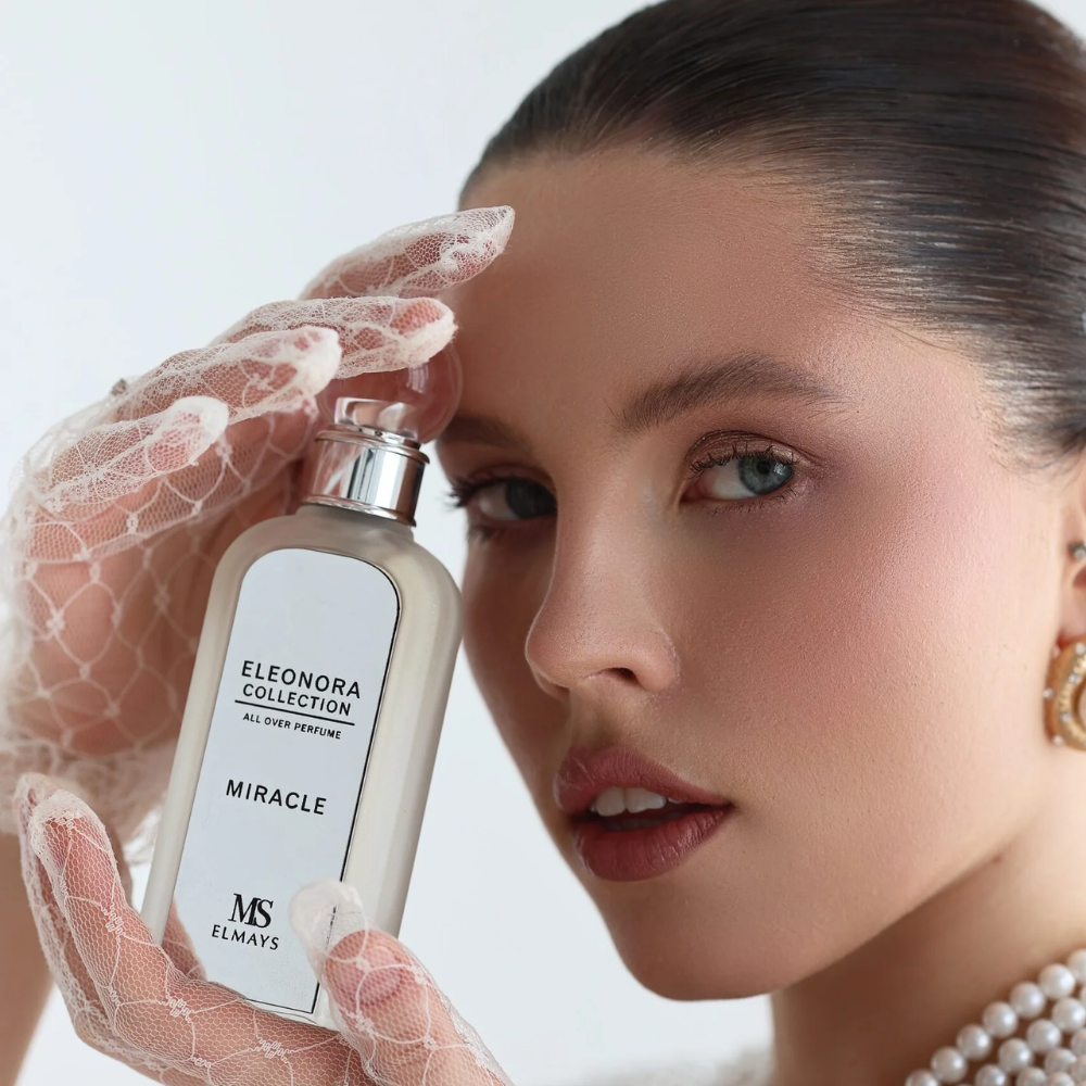 Woman holding a perfume bottle labeled 'Eleonora Collection Miracle' with a white background